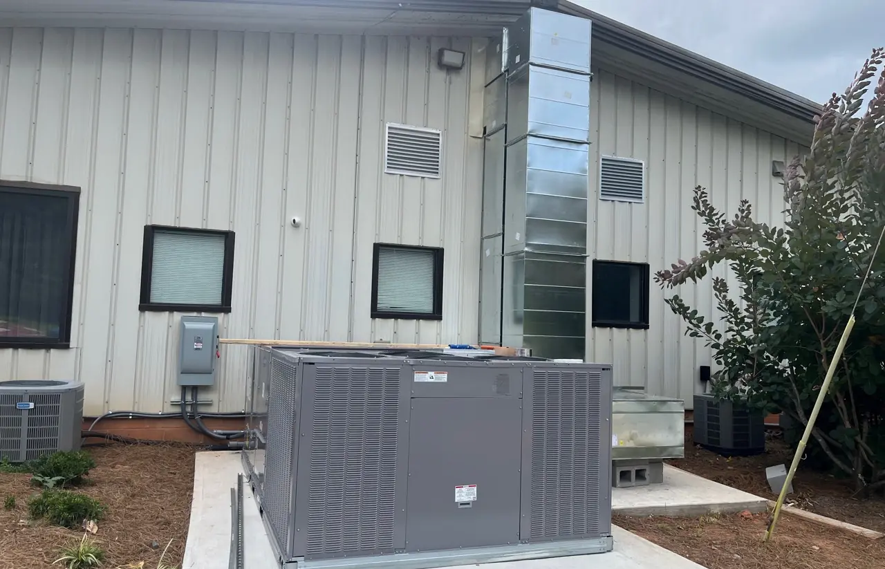 Commercial HVAC equipment and exterior ductwork beside a building